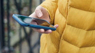 Teenager in yellow puffa jacket holding a mobile phone
