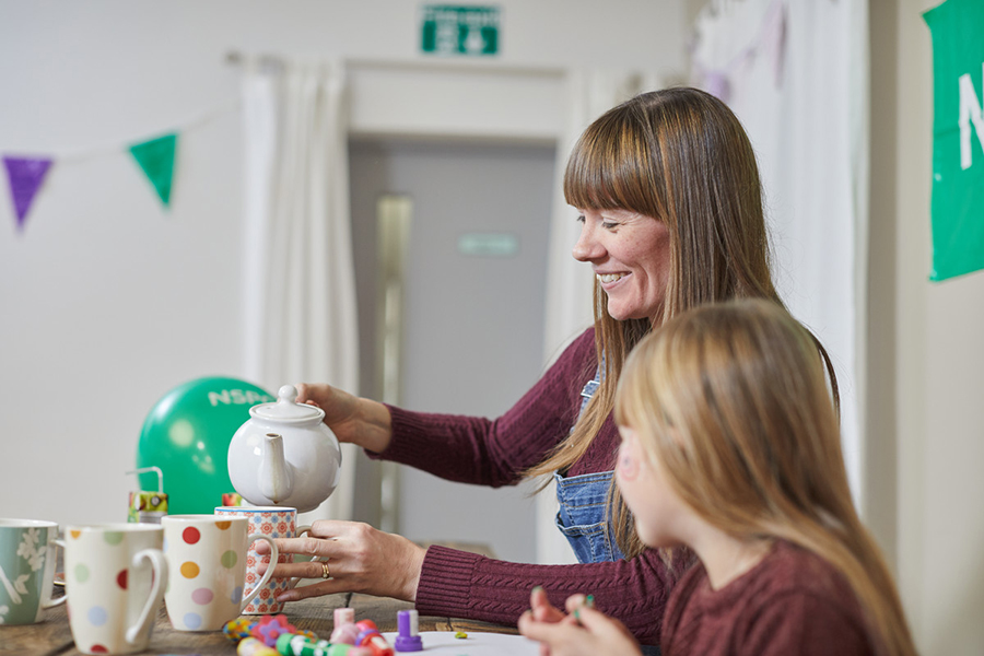 Woman and young girl pouring tea at a community fundraising event.