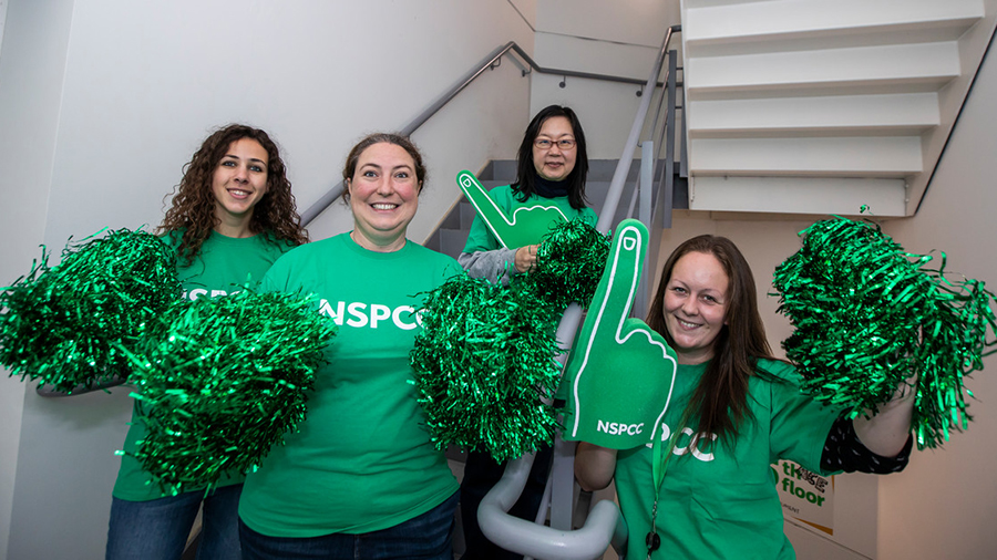 4 event volunteers standing on staircase with green pom-poms