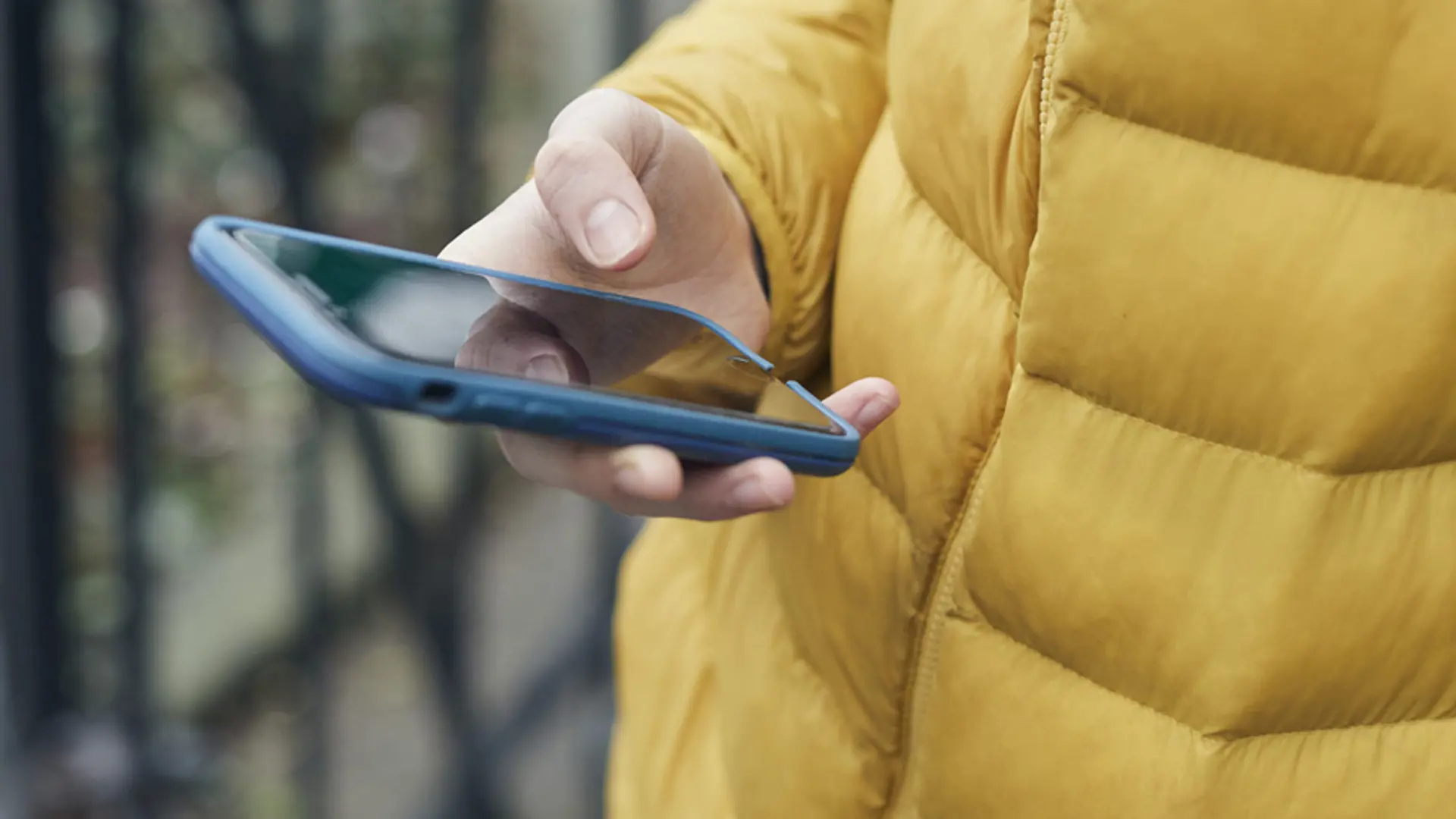 Teenager in yellow puffa jacket holding a mobile phone