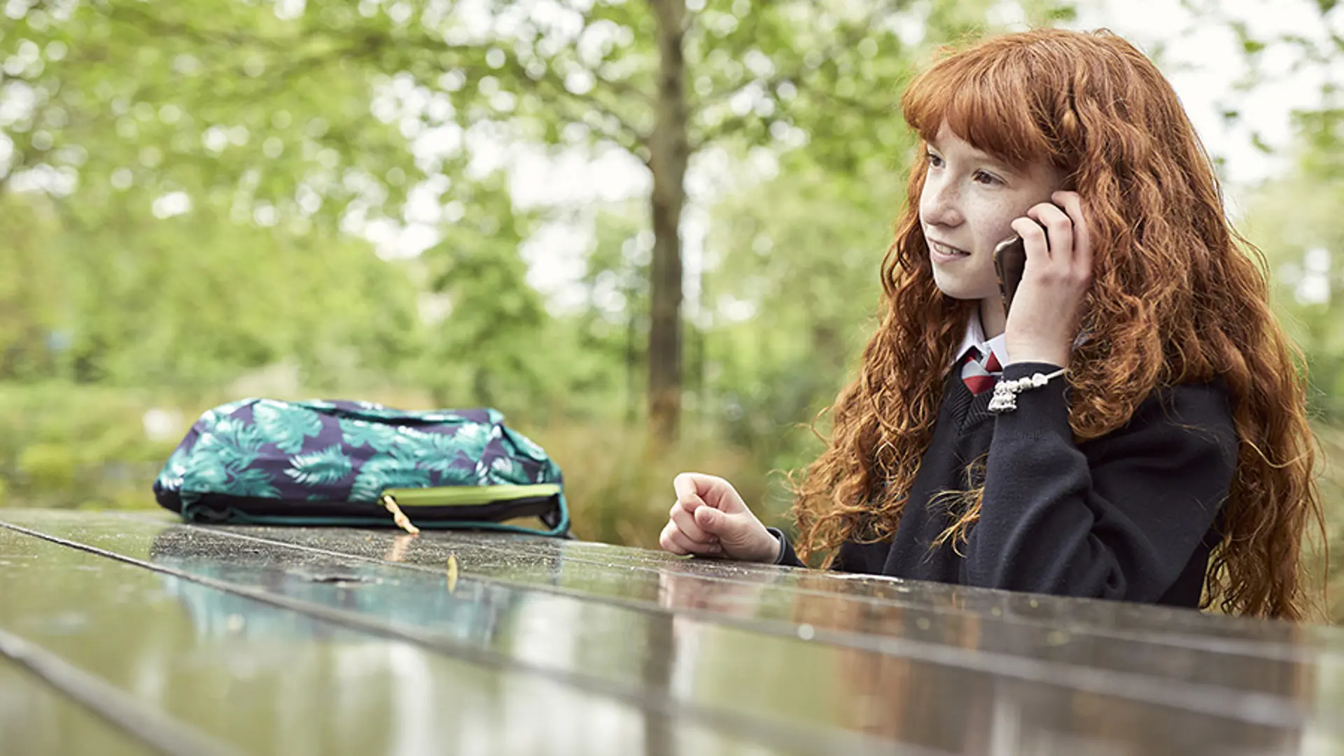A teenager smiling while on a call to Childline.