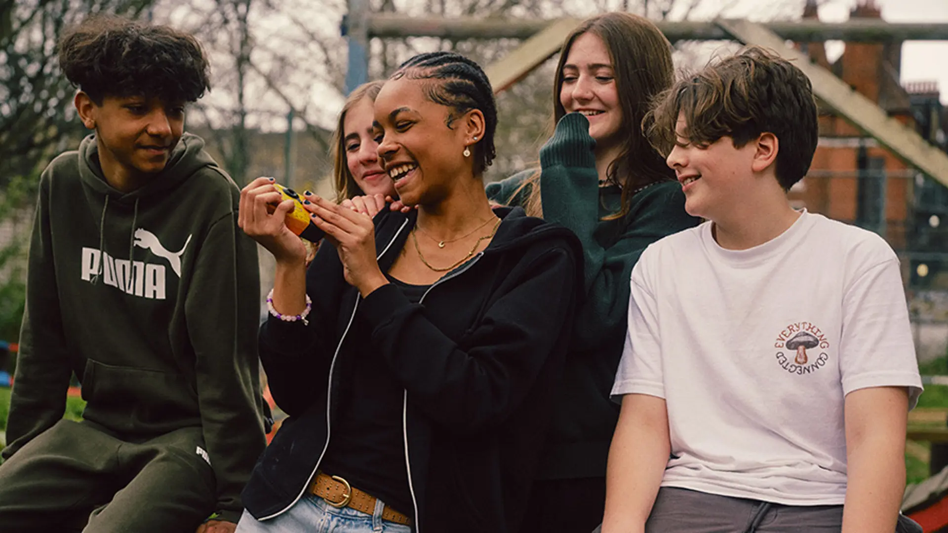 A group of teenagers smiling while socialising with each other.