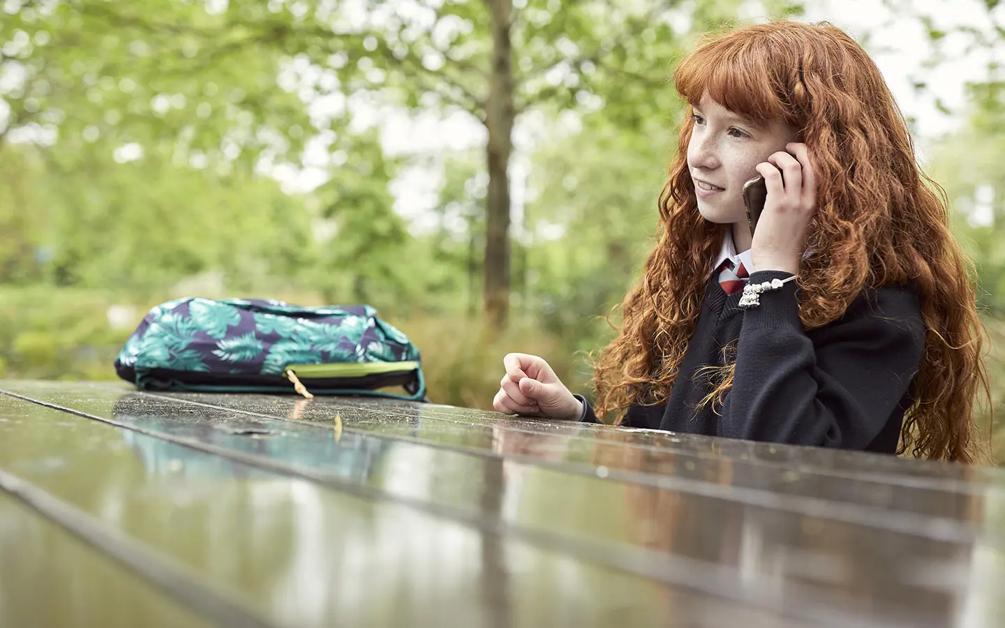 A teenager smiling while on a call to Childline.