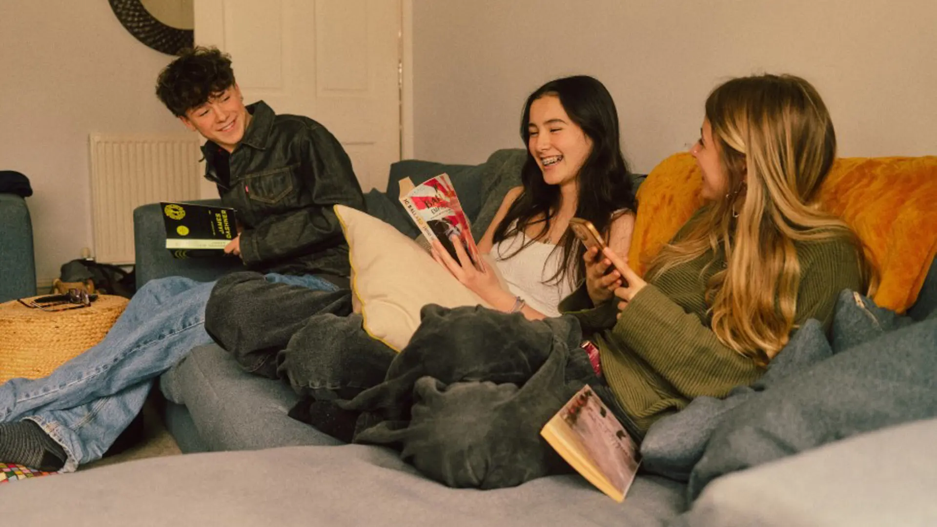 Photo of three young adults sat on a sofa.