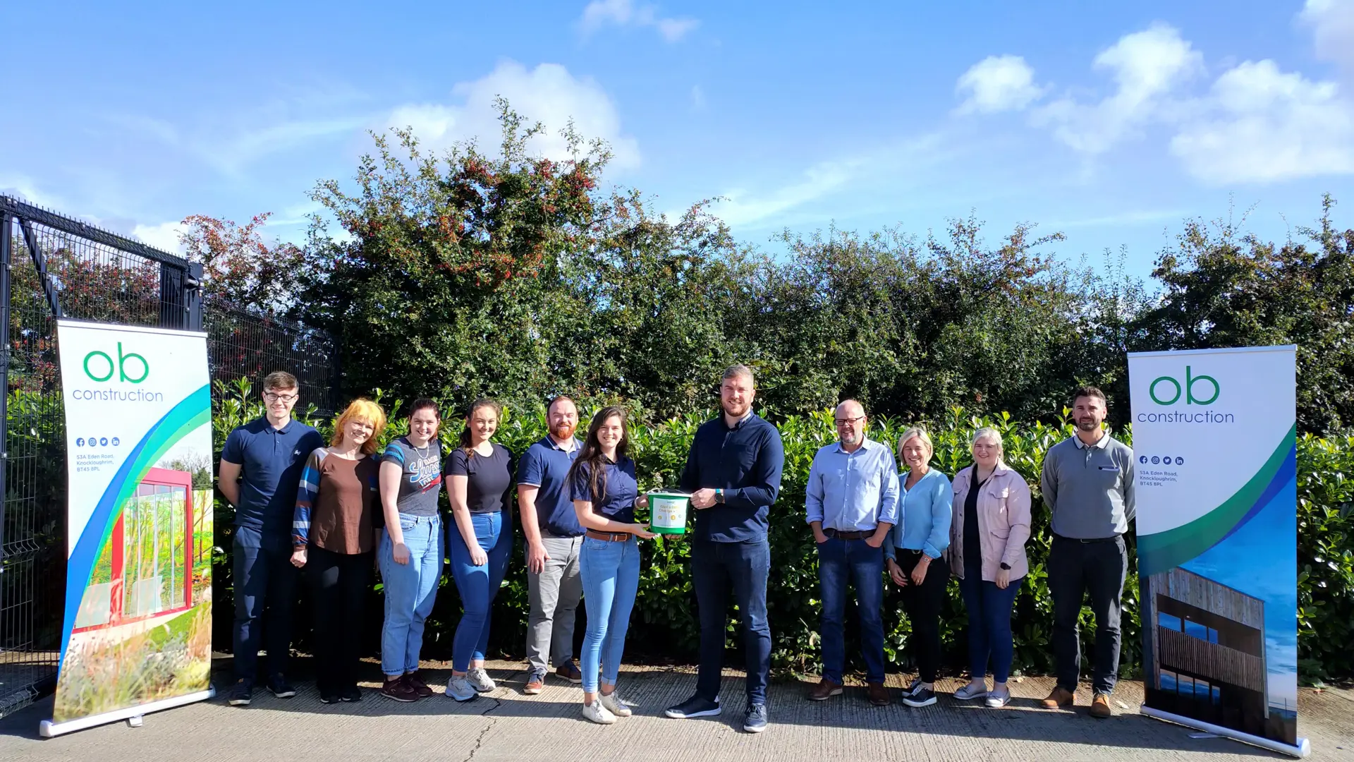 The OB Construction workforce posing with an NSPCC fundraising bucket.