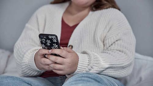 Photo of a teenage girl, she is holding a phone with both hands in front of her