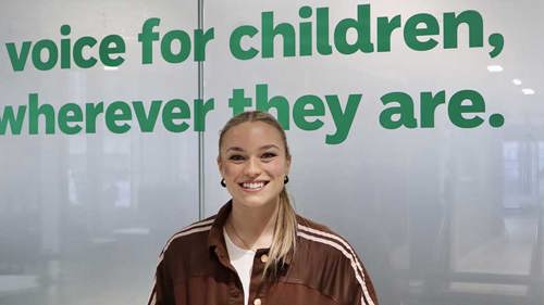 Image of Jodie at the Childline offices. She's smiling and wearing a brown tracksuit top.