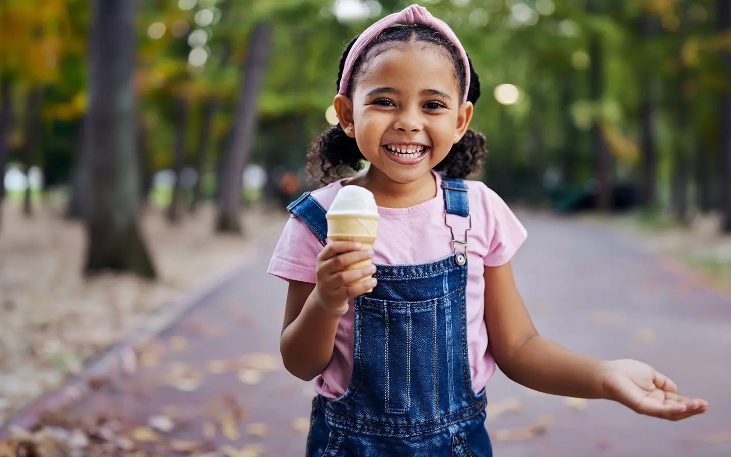 A young child smiling while eating an ice cream.