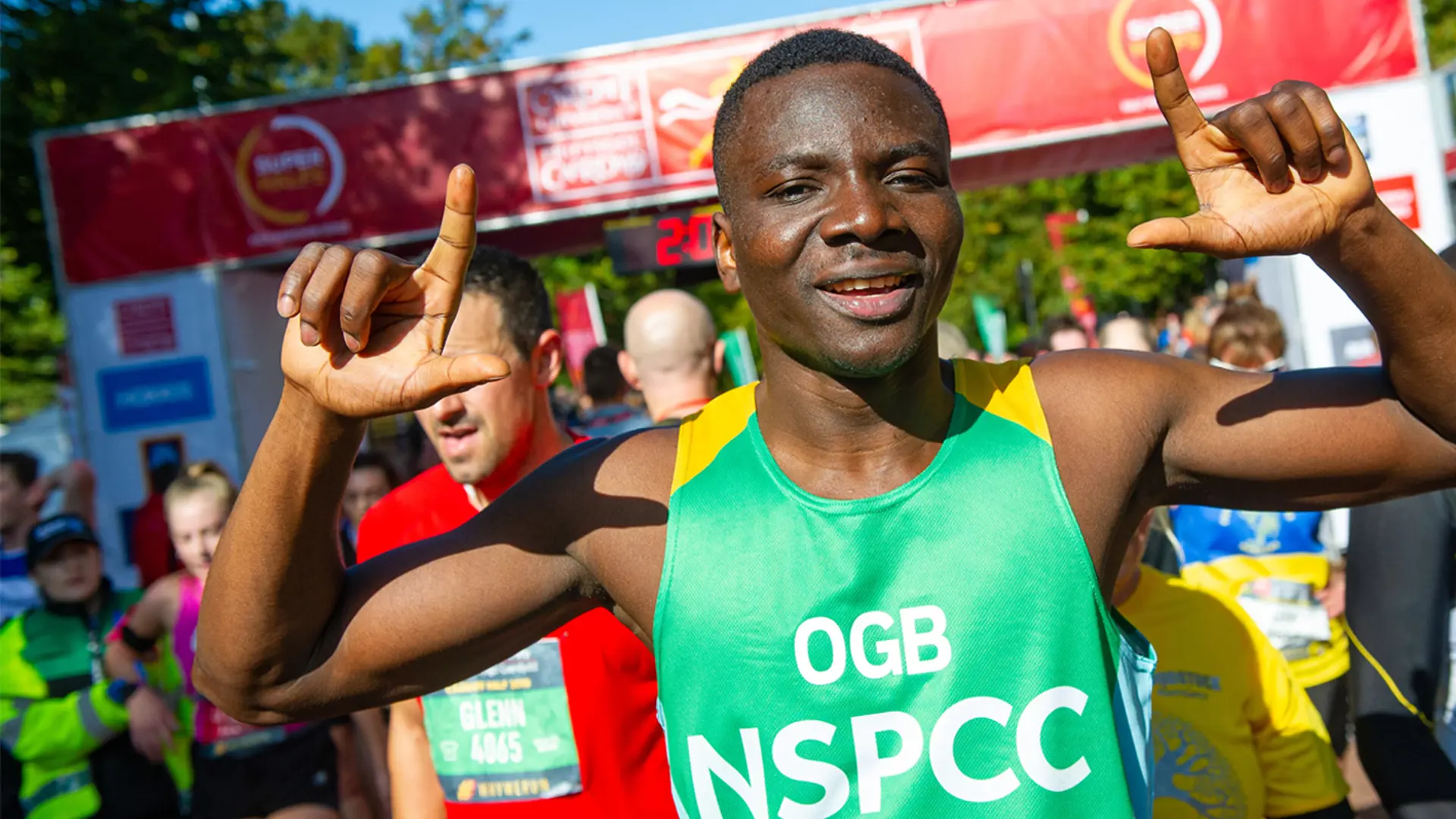 A man raising his hands to celebrate reaching the finish line of a half marathon