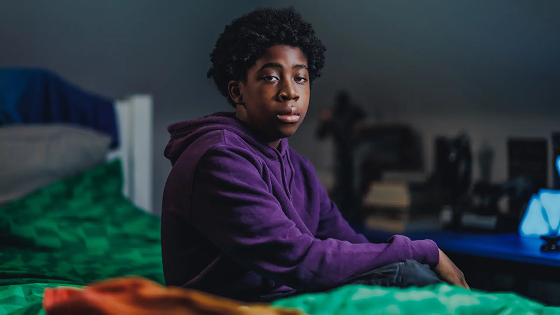 A teenager sat on their bed while staring into the distance.