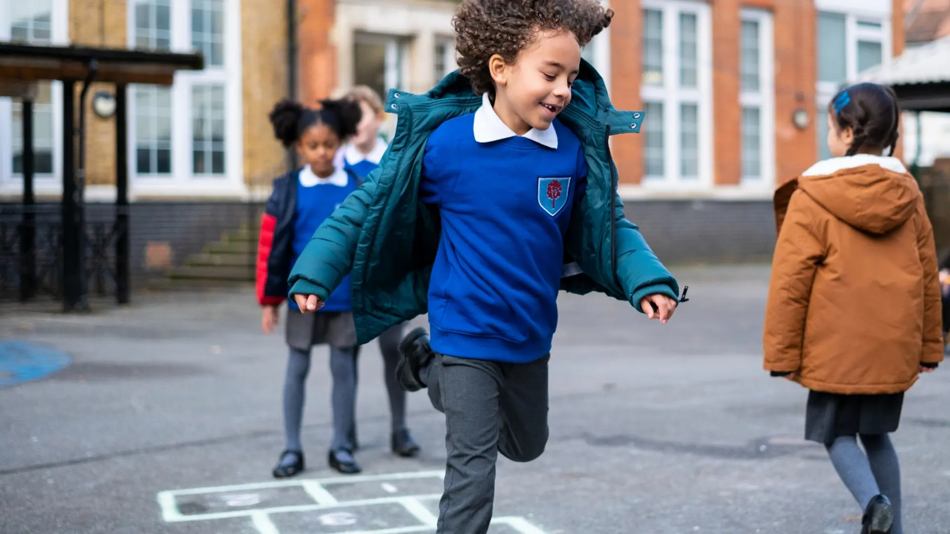 A young boy smiling while playing in a school playground.