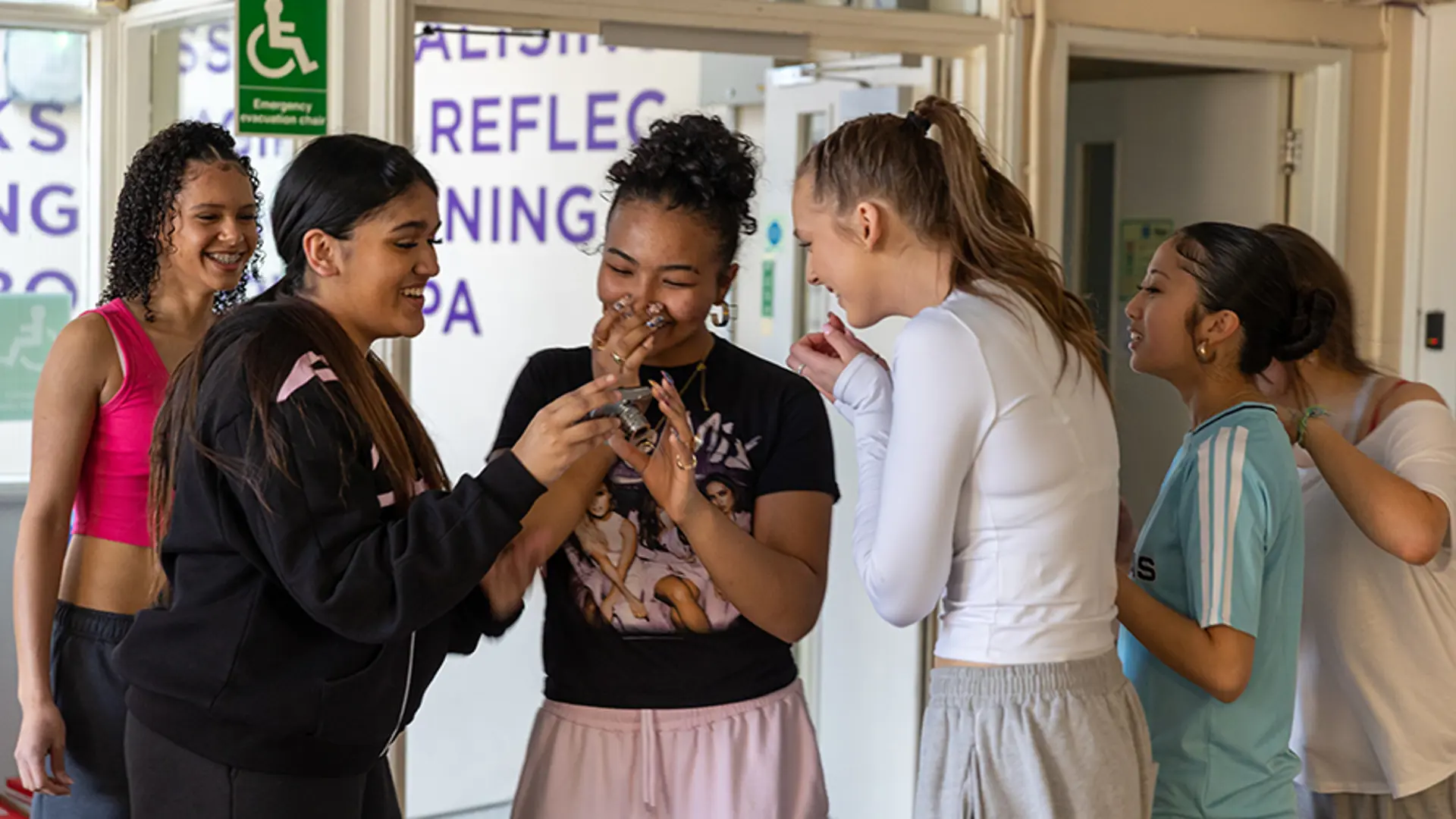 A group of teenagers laughing and smiling while taking part in a sports activity.