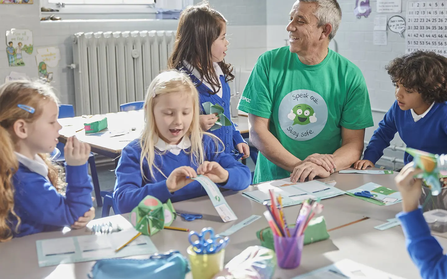 An NSPCC practitioner playing with young children at a school.