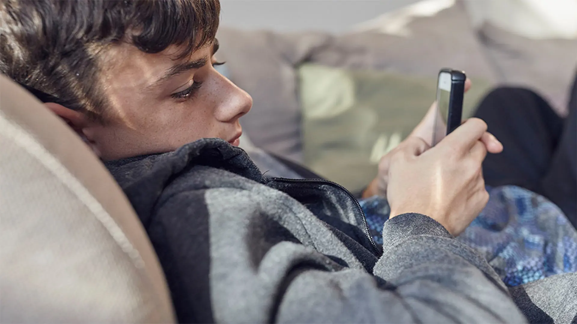 A teenager lay down while using their mobile.