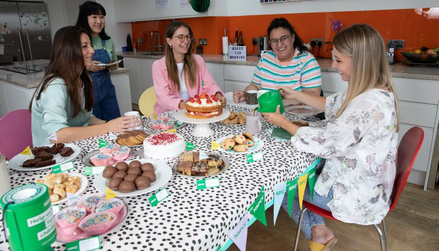 A group of friends laughing and smiling while at a coffee morning.