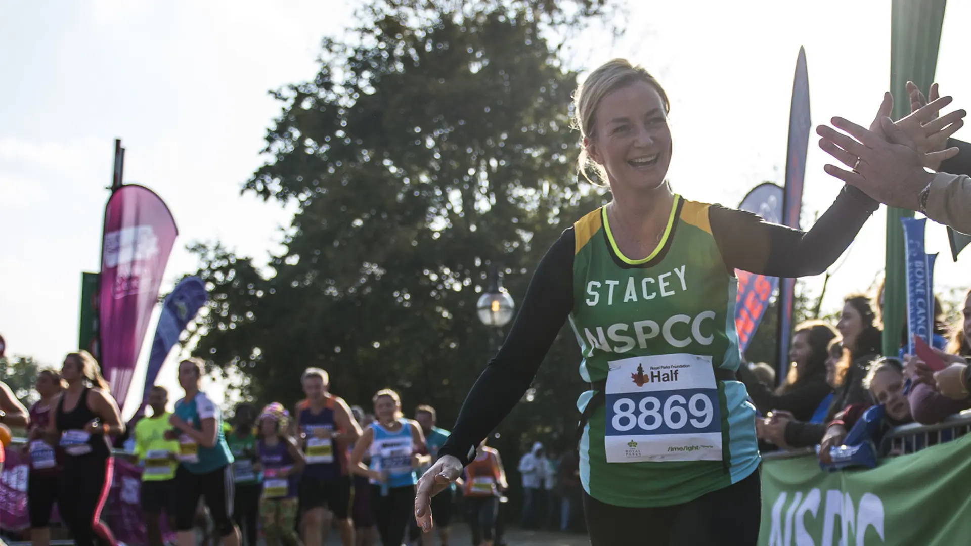 Woman in NSPCC vest running and smiling