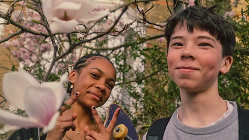 Two teenagers smiling while socialising with friends.