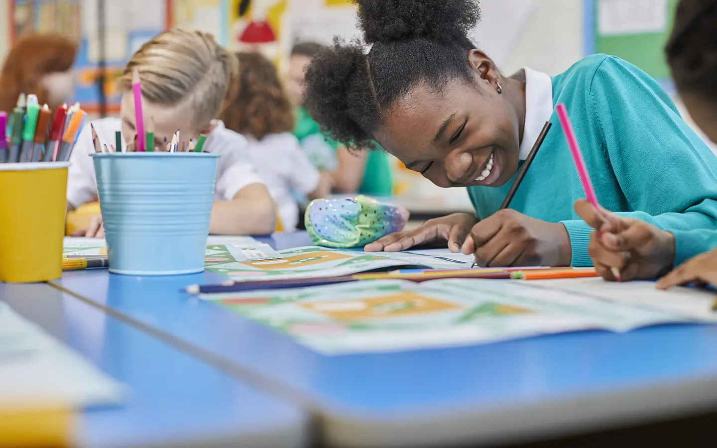 A young girl smiling while drawing at school.