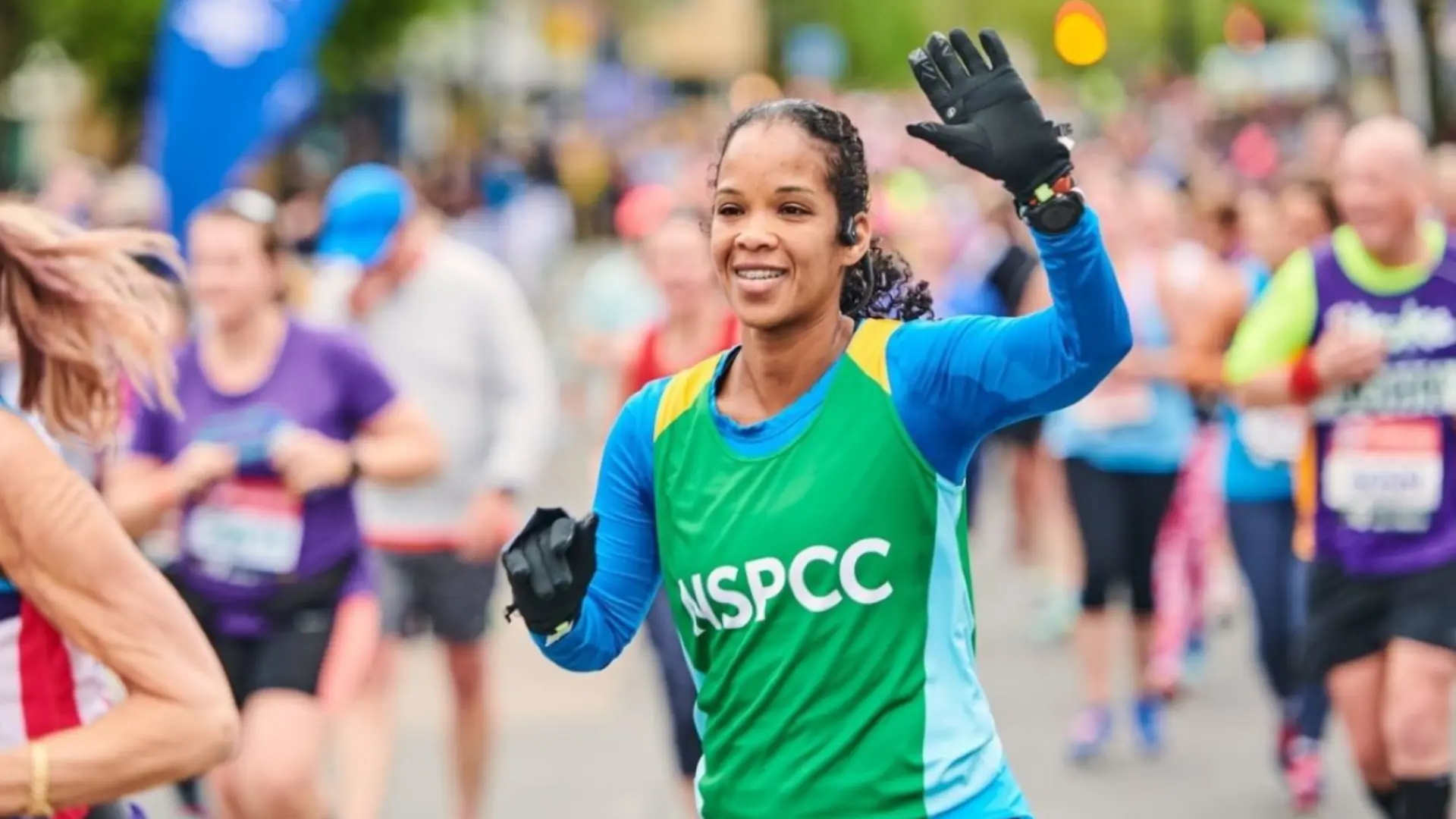 Woman in NSPCC vest running and smiling in Brighton Marathon