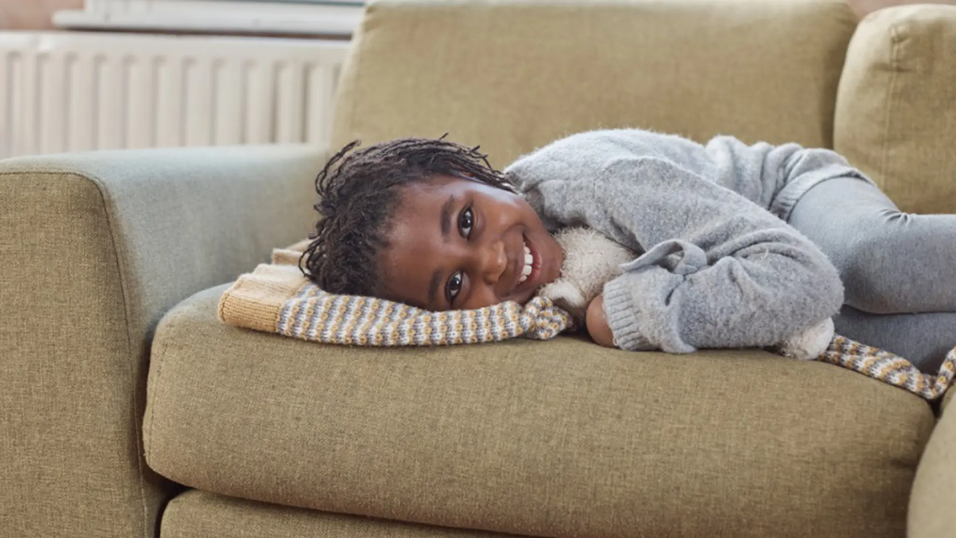 A child smiling while lying down on a sofa.
