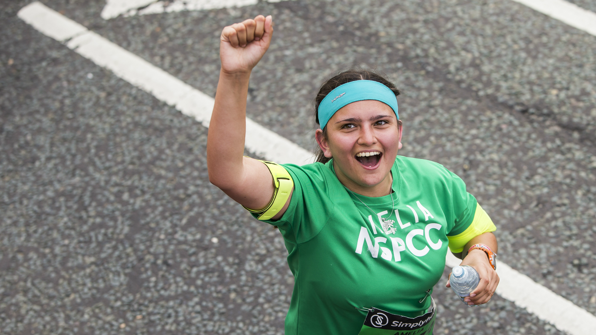 A Team NSPCC runner cheering while taking part in a race.