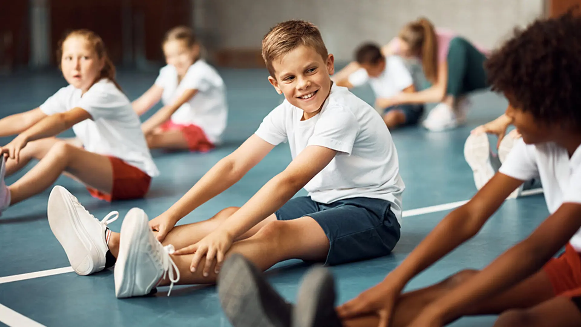 A teenager smiling with a friend while taking part in a sports activity.